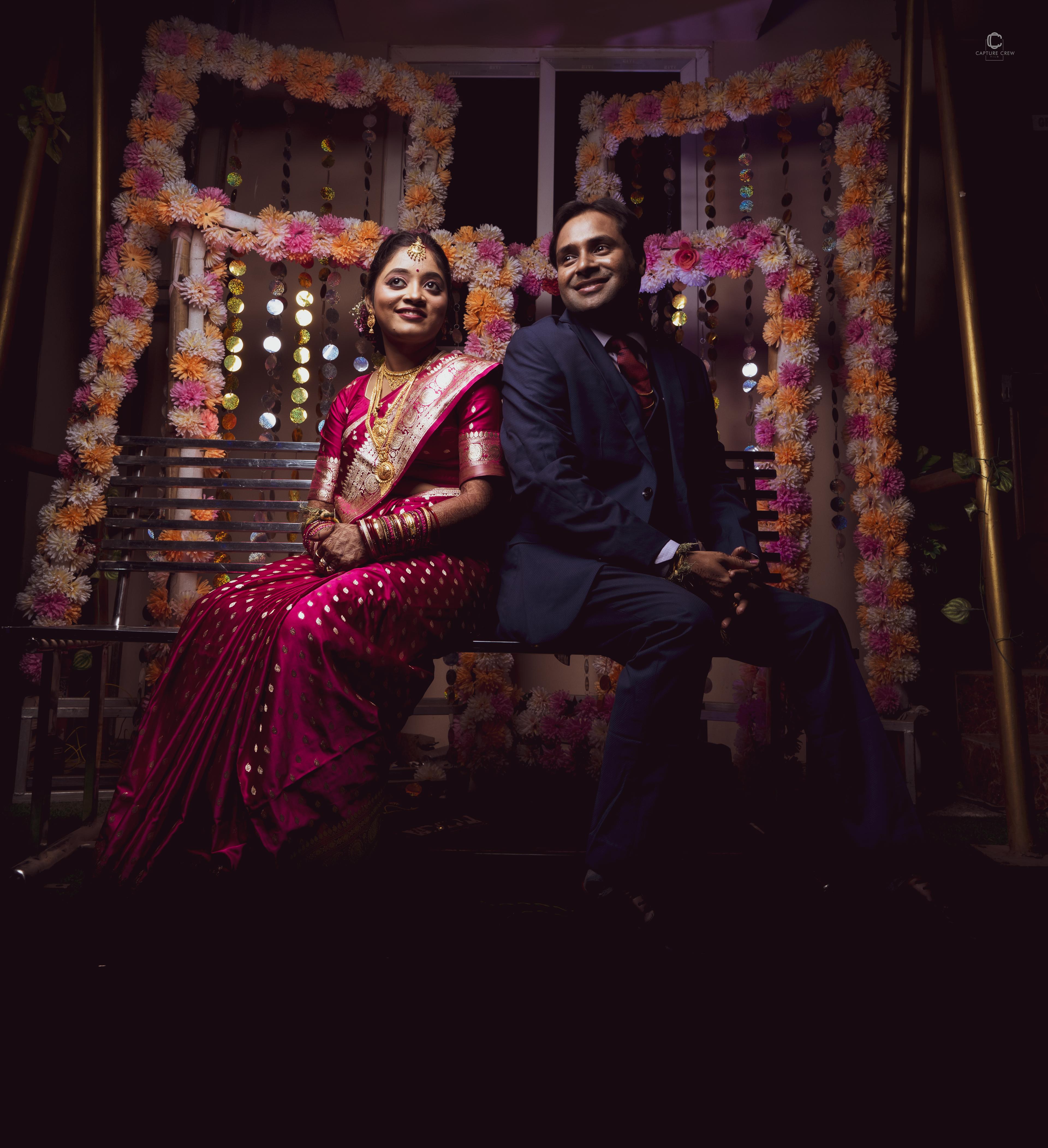 Elegant Indian wedding portrait - bride in red silk saree and groom in navy suit seated in floral decorated mandap - creative night photography with bokeh lights by CaptureCrew Films | TCCF Photography Bhubaneswar